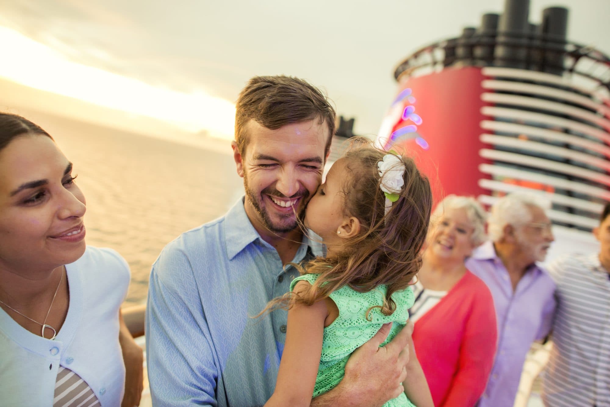 Familia de tres generaciones con una nena en brazos en la cubierta de un crucero Disney