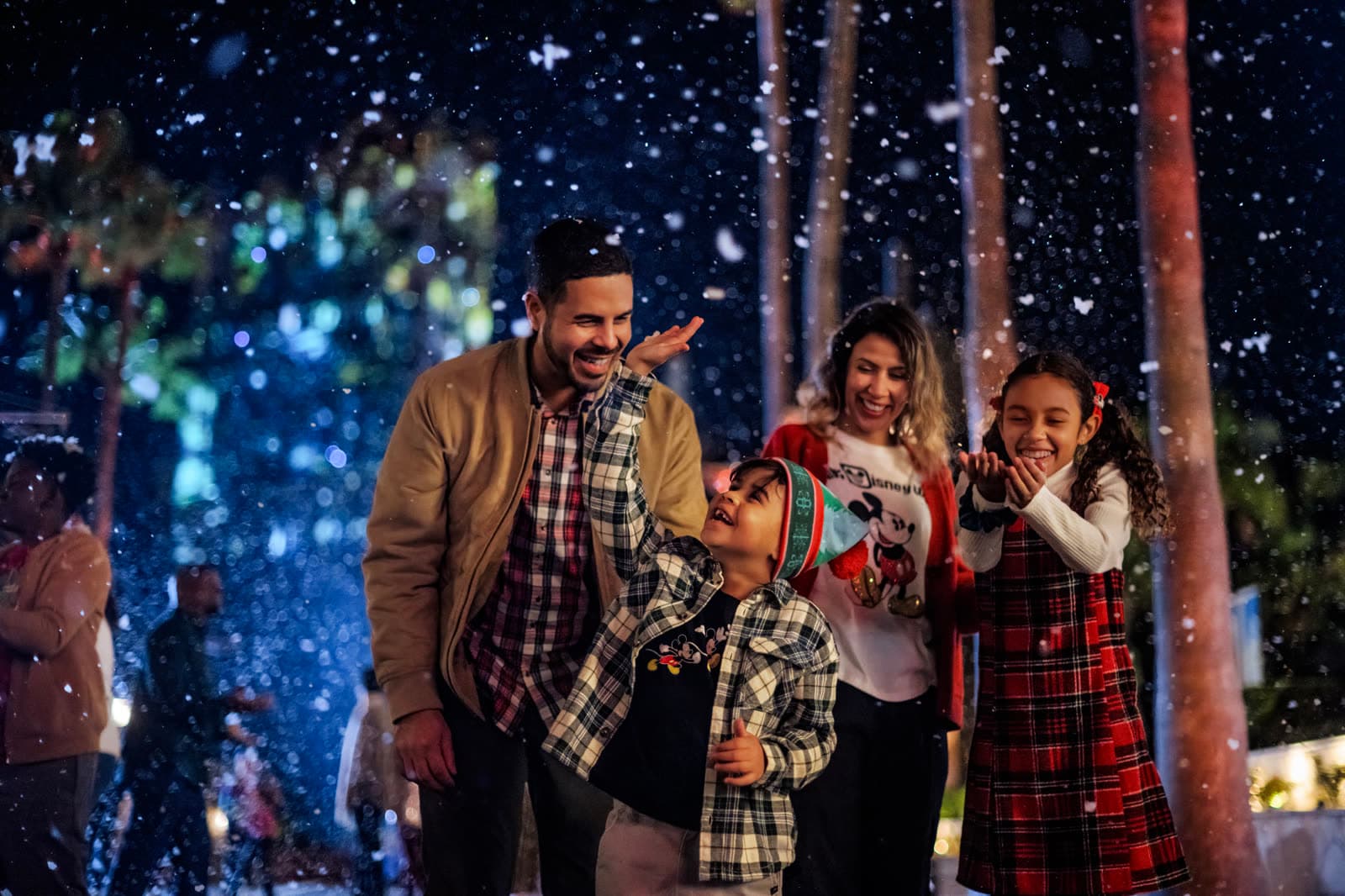 Familia disfrutando de la nieve nocturna en Sunset Boulevard