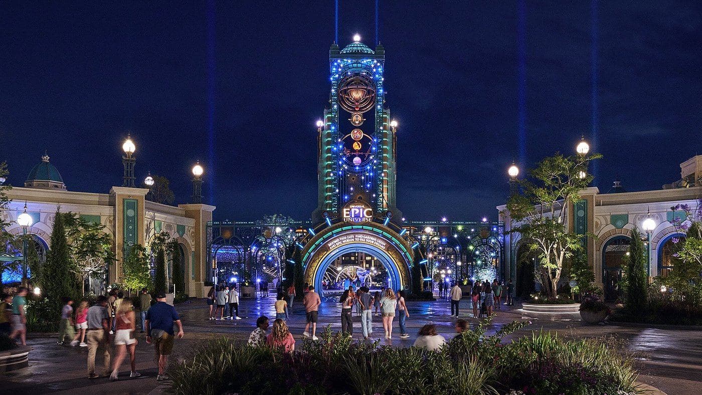 La entrada de Epic Universe iluminada de noche, con la torre de Celestial Park y el arco EPIC UNIVERSE en Universal Orlando