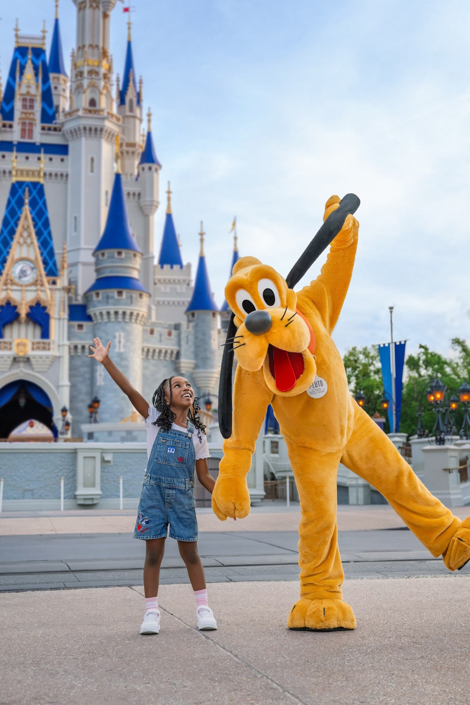 Pluto saludando junto a una nena frente al castillo de Cenicienta