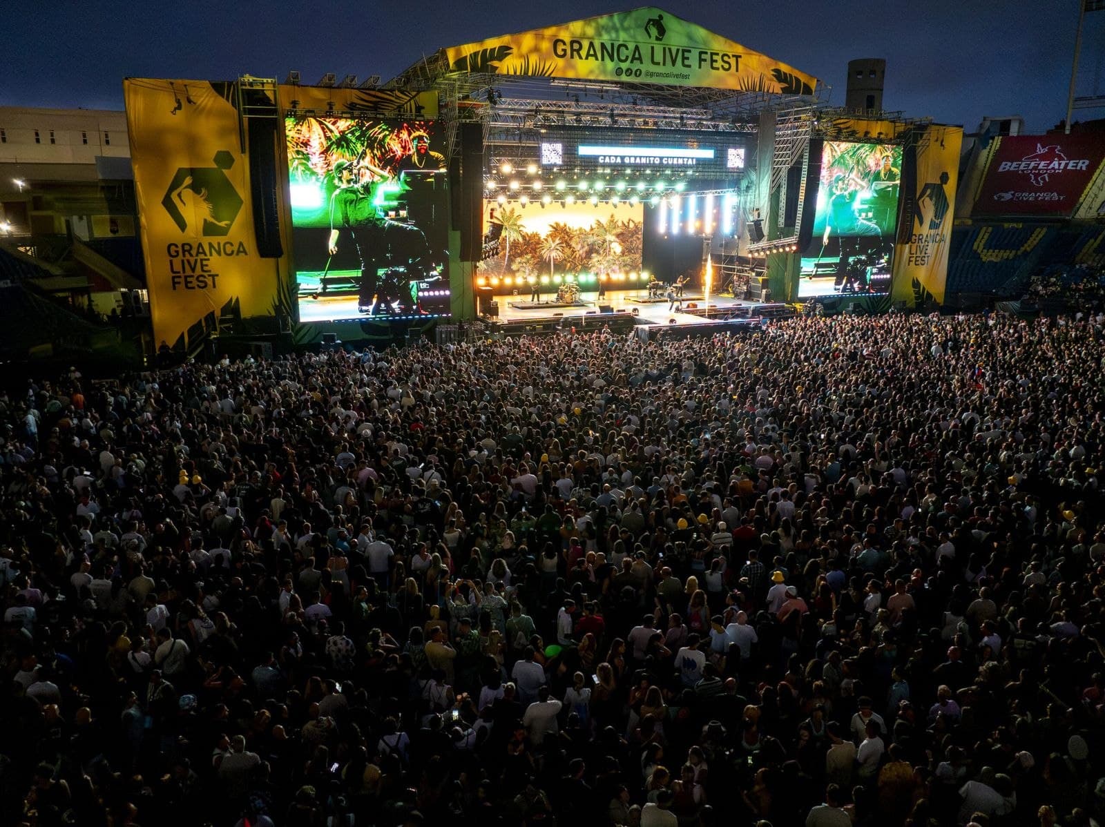 Vista aérea de un festival de música al aire libre con una multitud enorme frente al escenario