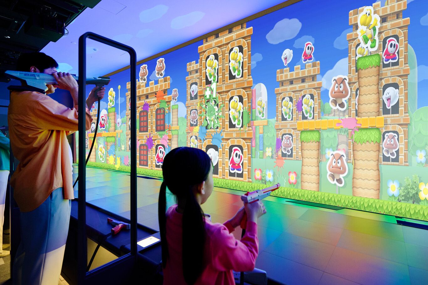 Visitantes jugando en una atracción interactiva de disparos con temática de Mario en el Nintendo Museum