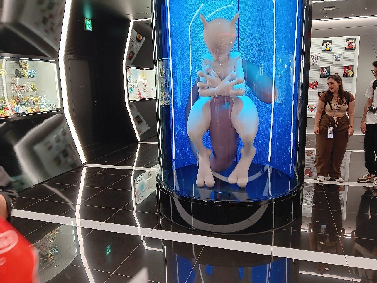 Escultura de Mewtwo dentro de una columna azul iluminada en un Pokémon Center de Japón